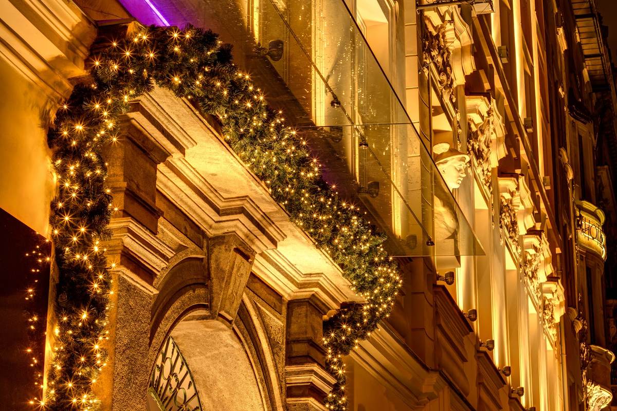 Historische Fassade mit Tannengirlande und warmer Lichterkette bei Nacht