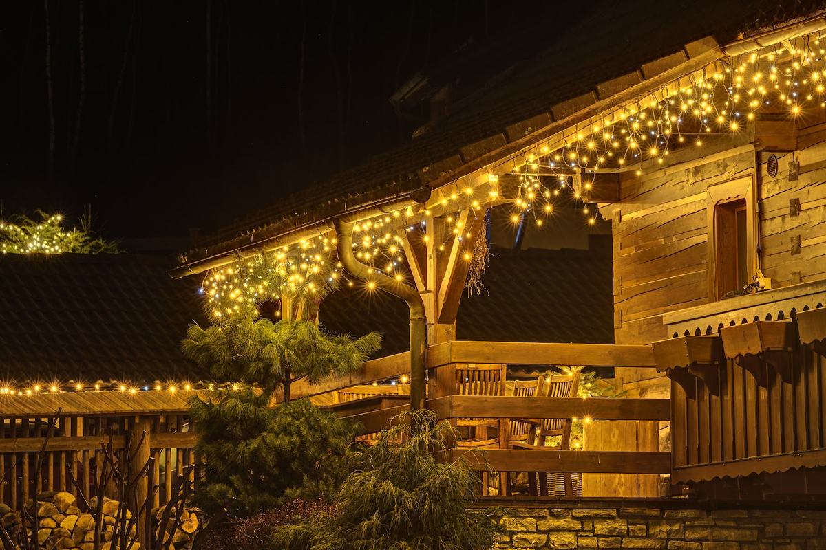 Holzhaus bei Nacht mit warmer LED-Lichterkette am Dach und am Balkon