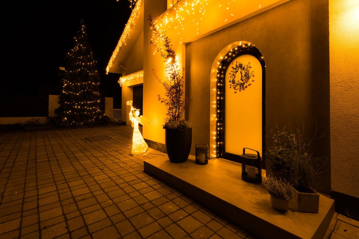Hauseingang bei Nacht mit warmer LED-Lichterkette am Türbogen und an der Fassade