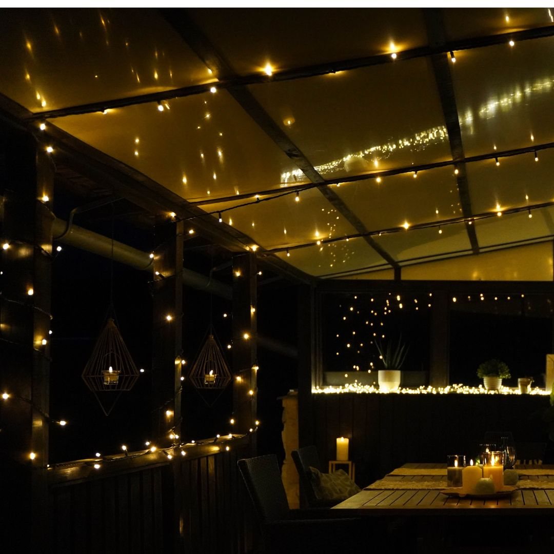 Überdachte Terrasse mit LED-Lichterkette am Glasdach und an der Holzwand
