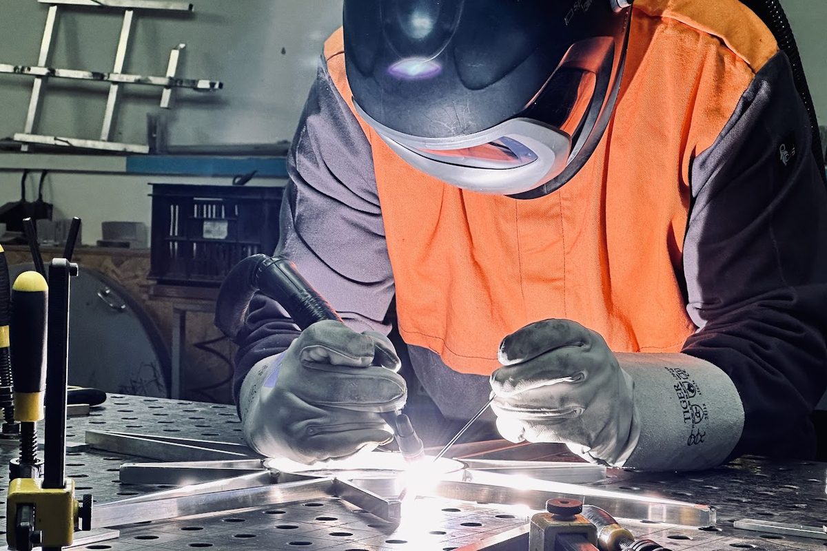 Ein Schweißer mit Schutzmaske schweißt die Metallkonstruktion eines Lichtsterns